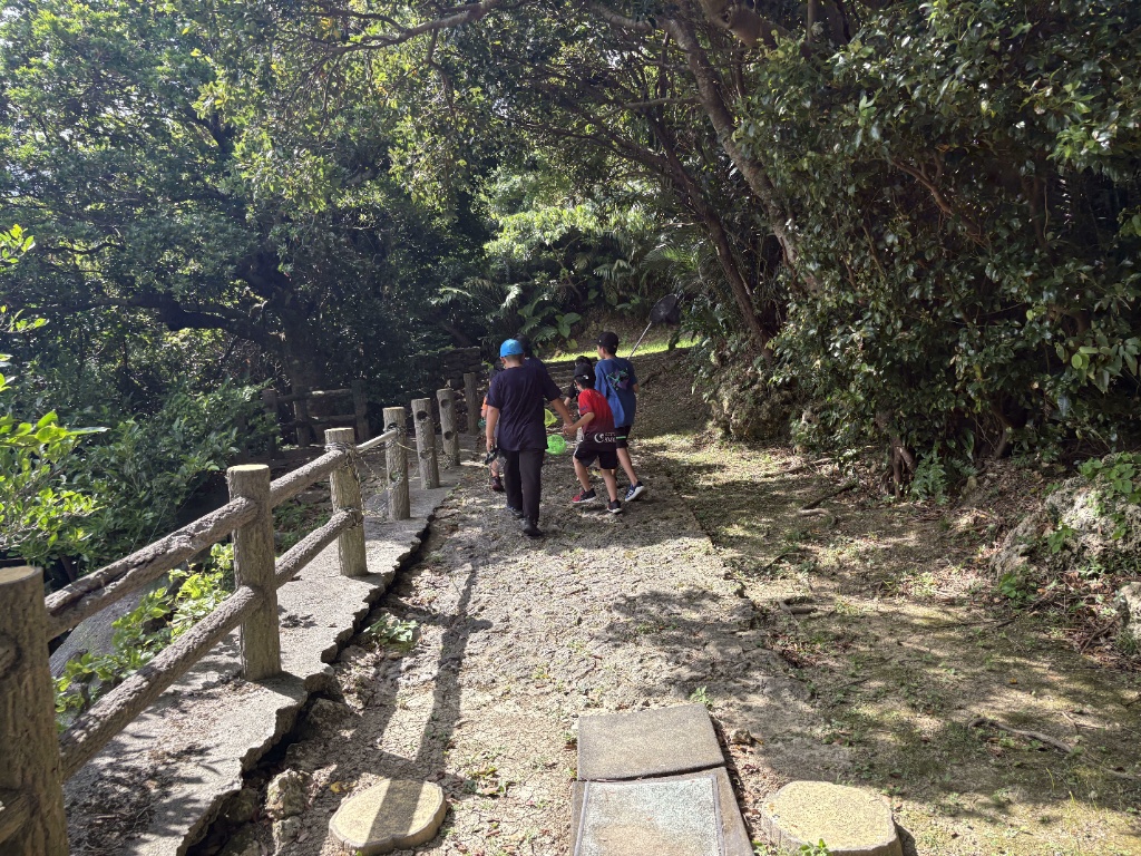 公園内の木陰の道を仲間と一緒に歩く子どもたち