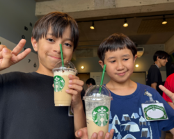 宜野湾市の放課後等デイサービス SOU NEXT ジュニア志真志にて、自分でトッピングした手作りドリンクを持ち笑顔でピースをする子どもたちの様子