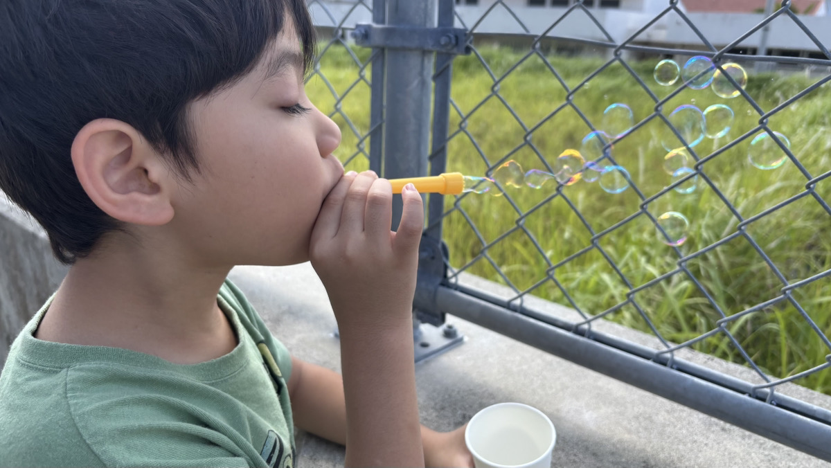カーテンを開けて朝日を浴びる子供